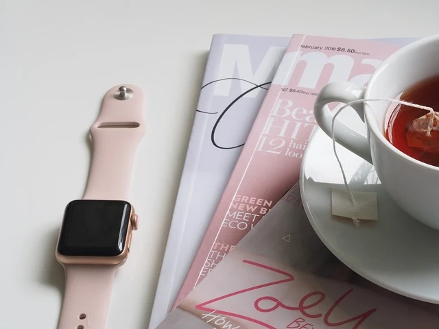 a table with magazines, cup of tea and an apple watch on the side