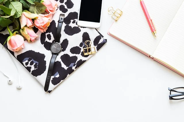 a table with a diary, pen on it, a mobile and flowers and watch on the side