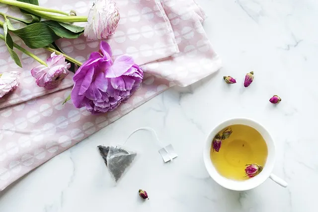 a table with a towel, flowers and a cup of golden tea