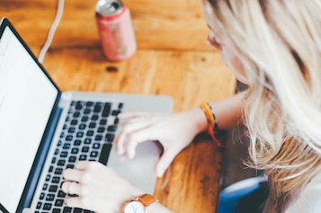 a table with laptop on it and a girl working