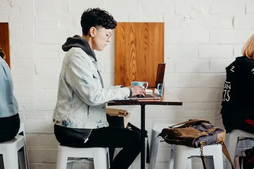 a man sitting on a table with a laptop on the front working 