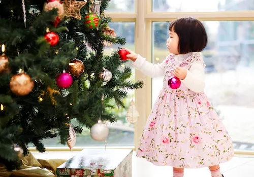 The image has a christmas tree with a small kid next to it. Used for a blog post on how to make money as a kid