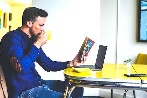 a yellow circle table with a guy reading a book and drinking coffee