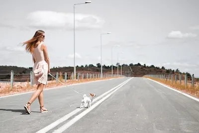 a road with a girl walking her dog