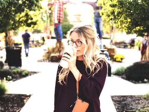 A woman with a starbucks coffee mug in hand and in the garden