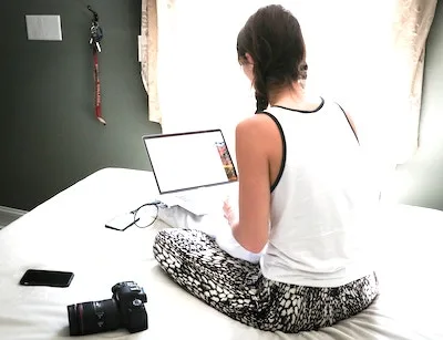 woman siting with the laptop on bed entering data