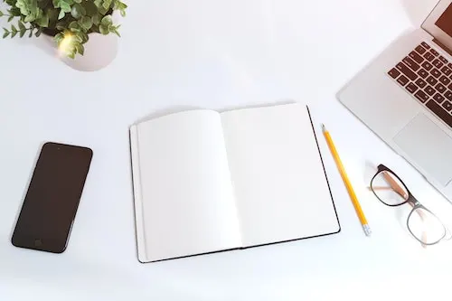 a blank notebook on a table with a pencil - blog graphic for companies that pay for ideas
