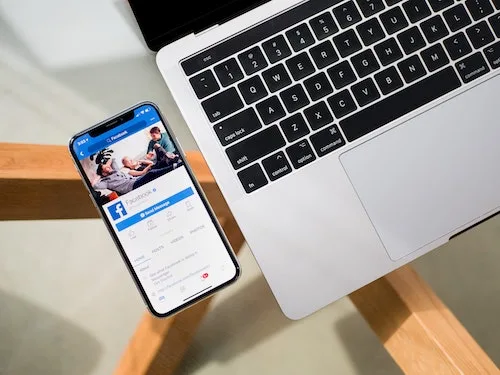 online yard sale - phone with facebook on it kept beside a laptop