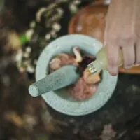 a hand pouring honet into a mortar and pretzel. Used as a blog post graphic forHow to make beauty products to sell or gift