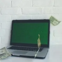 a laptop with money notes on it kept in front of a white wall