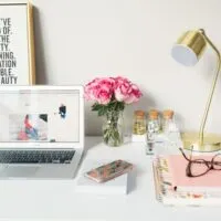 a table with laptop, lamp, books and flowers. Used for a blog post on best things to sell on ebay for profit
