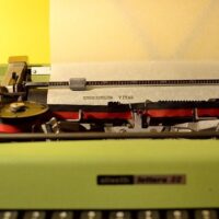 Green typewriter on a table. Used for a blog post on Online Typing Jobs Without Investment