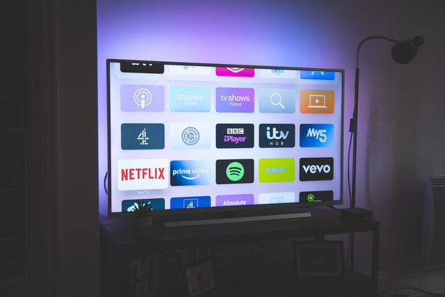 This image has a TV kept on a table. TV is open and is showing to browse Netflix, vevo, prime fideo, tv shows, itv, 4 etc. Graphic used on a post on how to get paid to watch tv