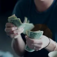 A guy counting cash in his hands. Graphic for a blog post on highest paying work from home jobs without a degree