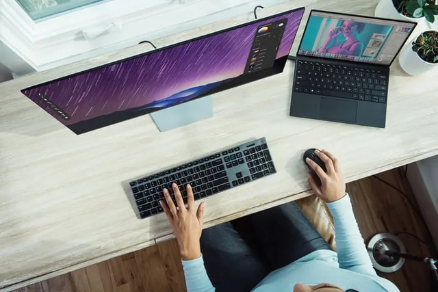 This picture includes a laptop, a monitor, keypad, a mouse. Someone is operating the desktop