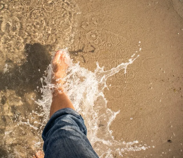 In this image a man is trying to splash the water with his feet