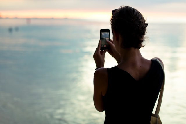 In this image a women is clicking pictures from her mobile phone 