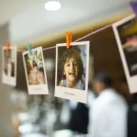 In this image few pictures of cute kids are hanging on a thin rope