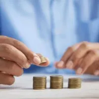 A man counting and add coins to the money.