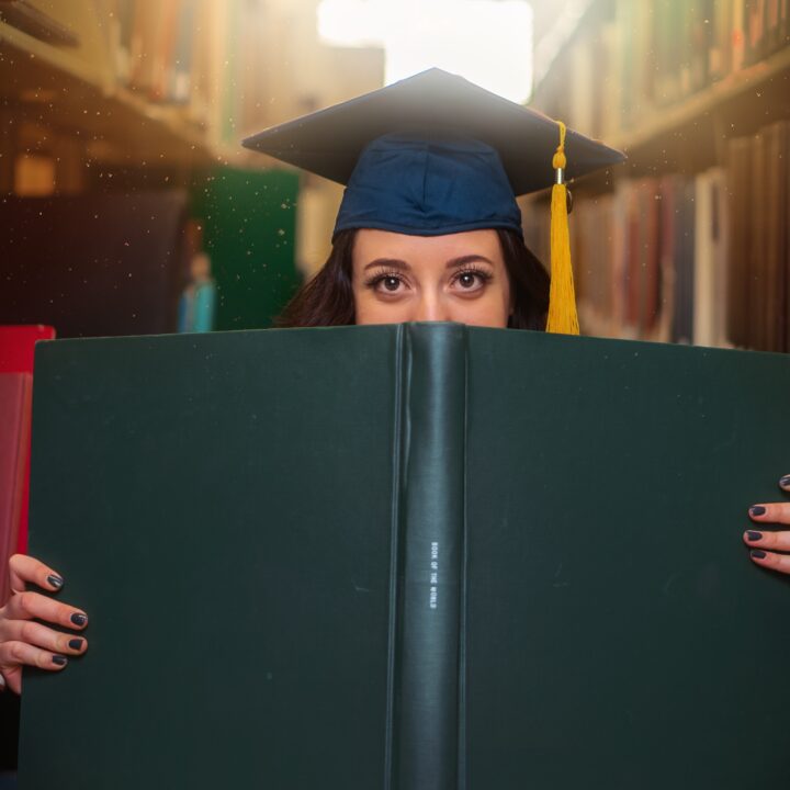 a grad student with the hat and book in the front hiding the face