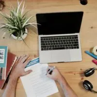 a table with laptop, headphone, plant and books on it