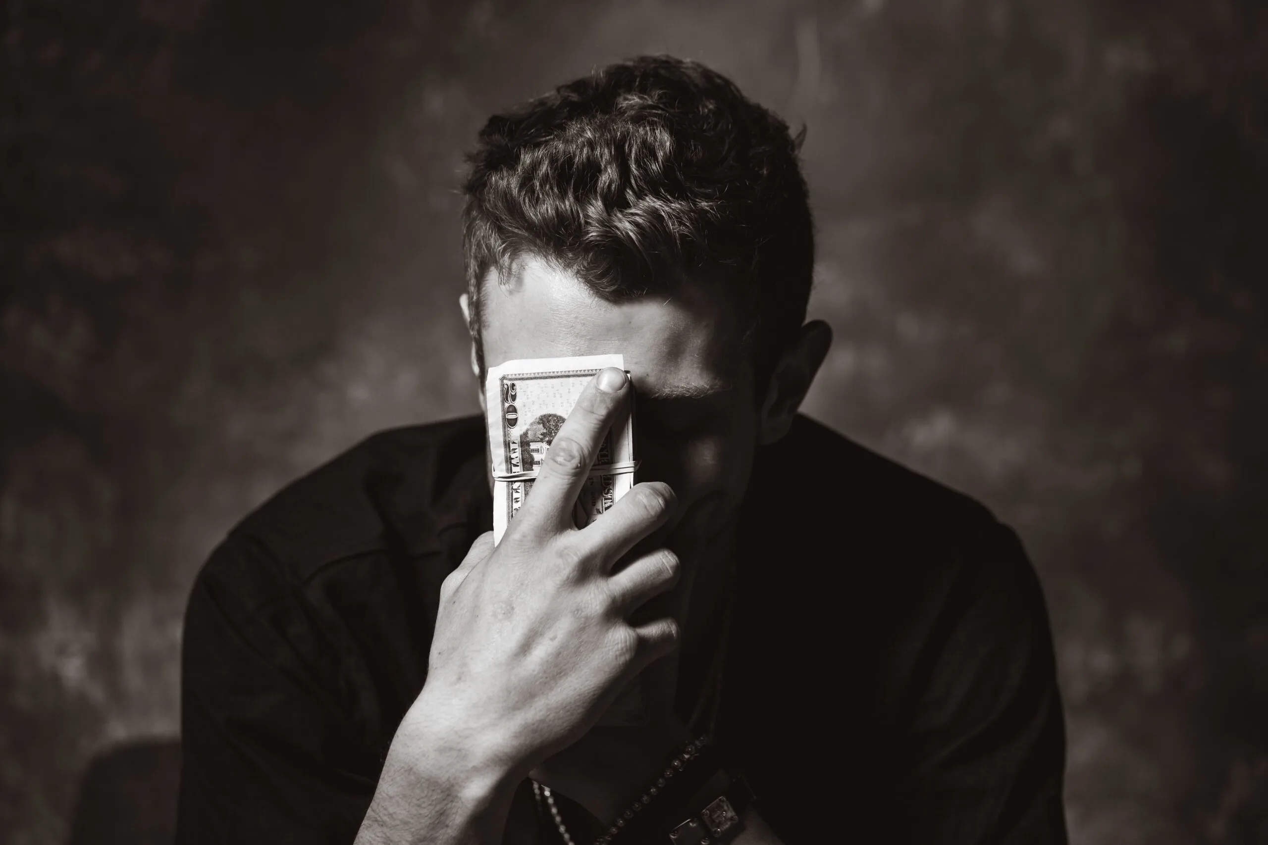 A man with money in his hand and in front of his face