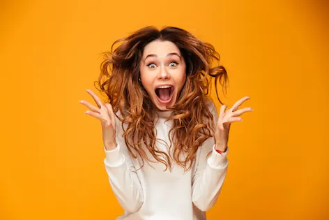 Image of excited screaming young woman standing isolated over yellow background. Looking camera.