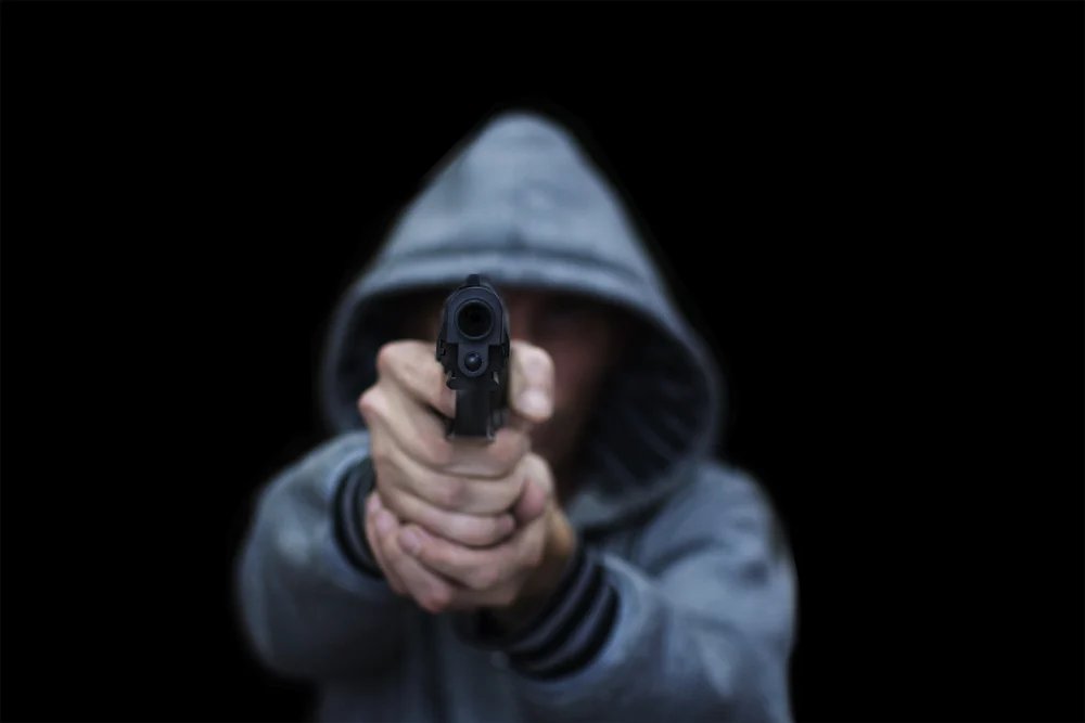 A man aims from a pistol. Isolated on a black background. The concept of threat, danger, defense