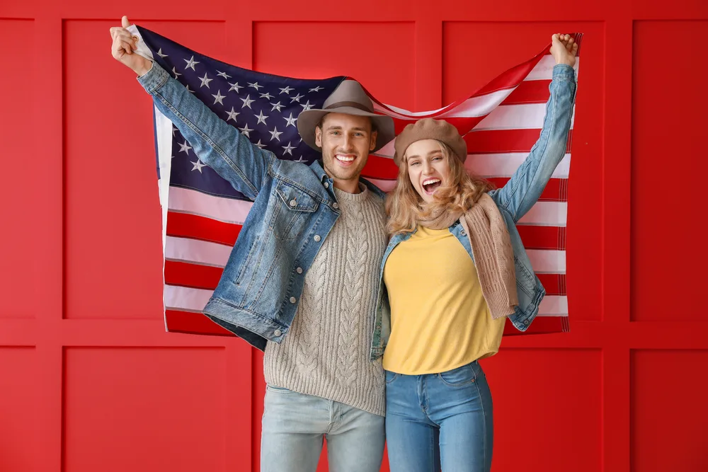 Young couple with USA flag on color background. Memorial Day celebration