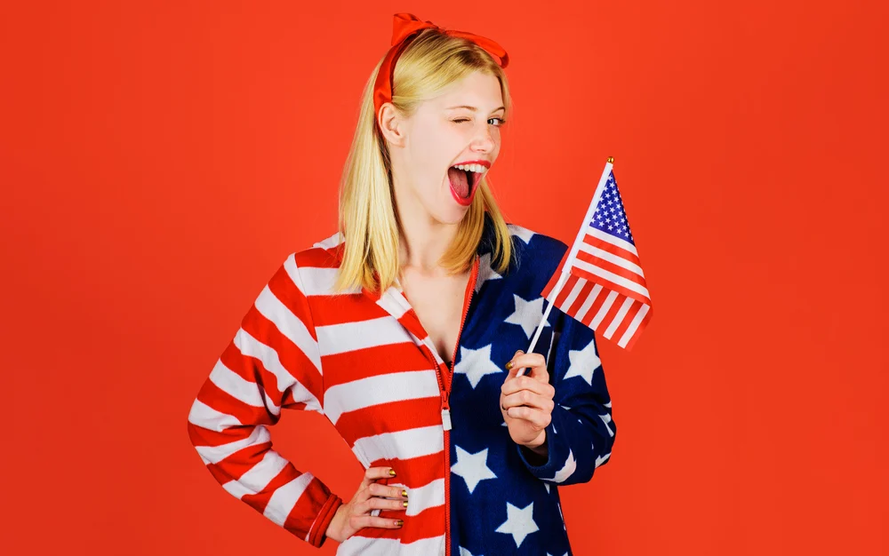 ependence Day celebration. July 4th. Winking girl with American flag. National colors USA