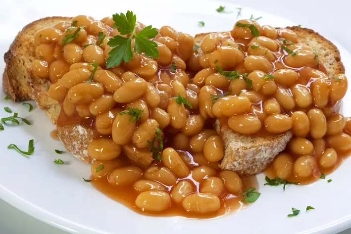 Baked beans on sourdough toast, garnished with parsley.