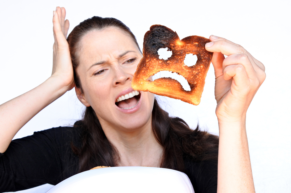 Woman scream at a burnt slice of toast with an unhappy smiley face. Sadness concept. Real People. copy space