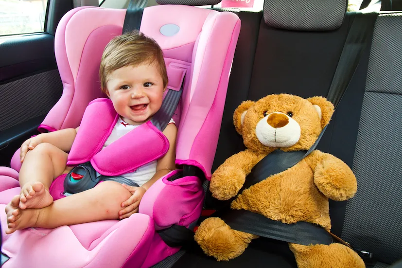 Baby girl with his teddy bear smile in car