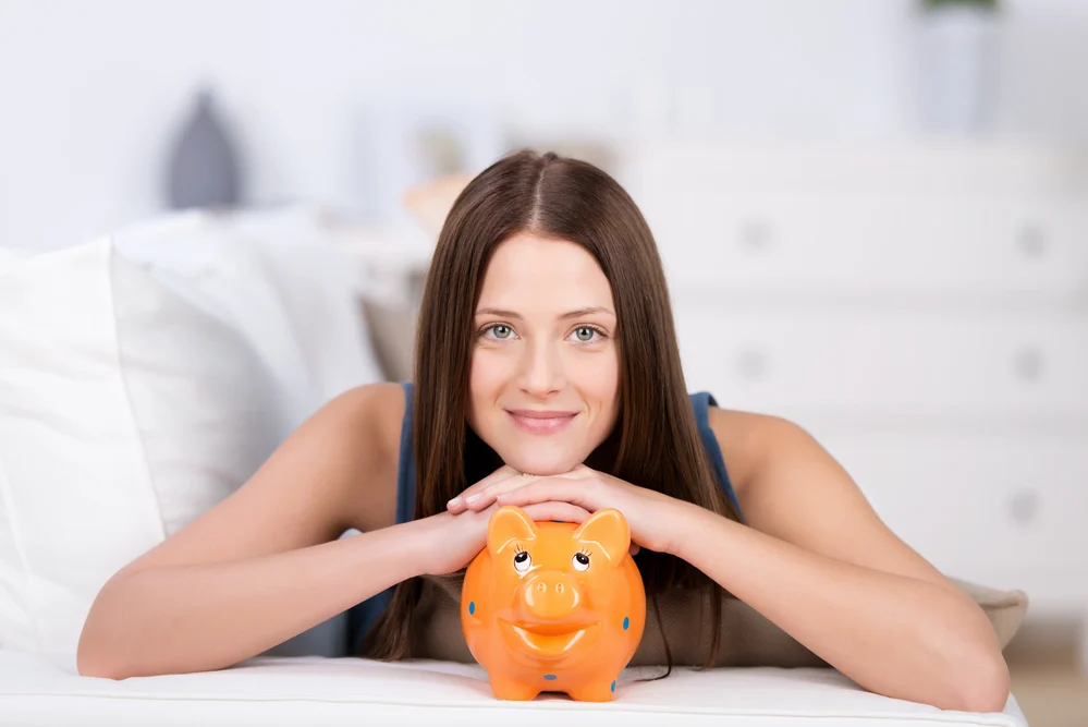 Portrait of long hair woman in bed holding a piggybank