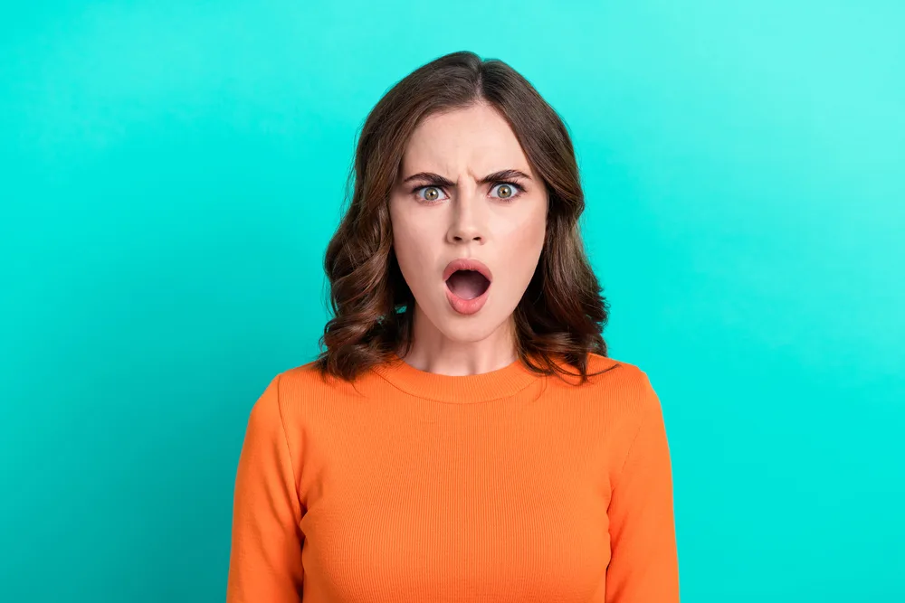 Photo portrait of young excited funny nervous stressed brown wavy hair lady open mouth dissatisfied bad news isolated on aquamarine color background.