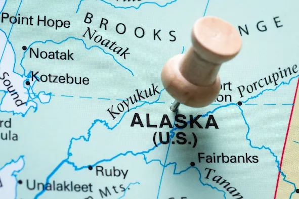 push pin marking Alaska on a world map as a destination concept