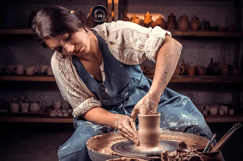 Stylishcraftsman works with clay on a potter's wheel. Artisan production.