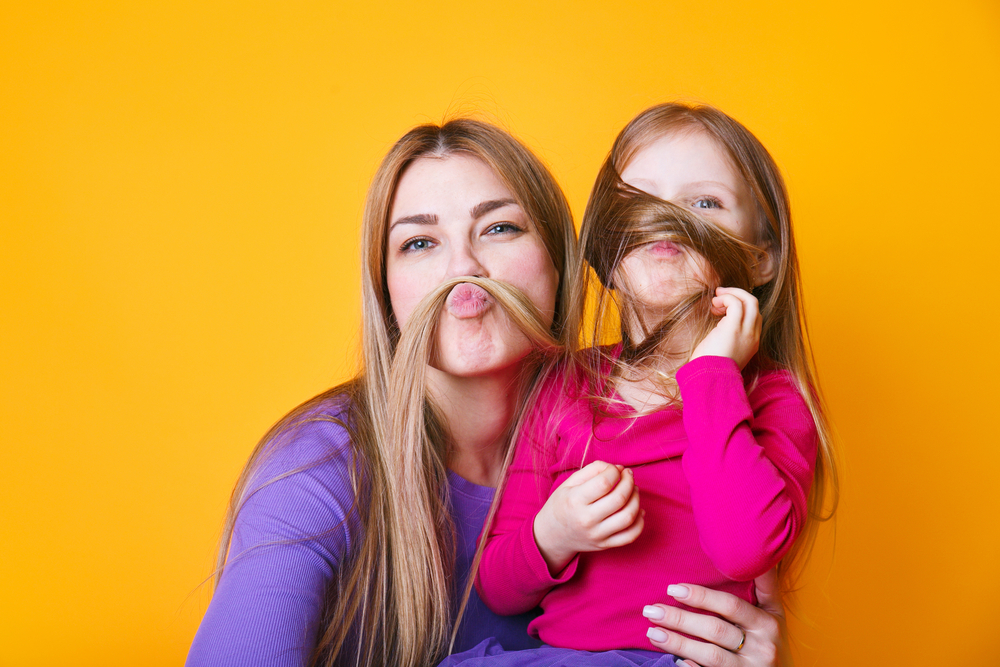 Close up photo amazing beautiful mom and small little daughter make moustache with curls pretend guy man on yellow background