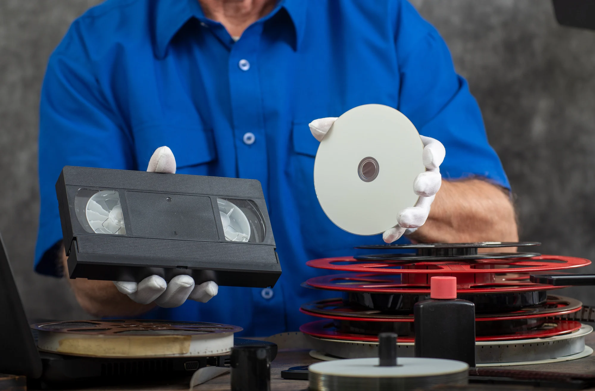 hand photographer holding a VHS tape and DVD disc for conversion