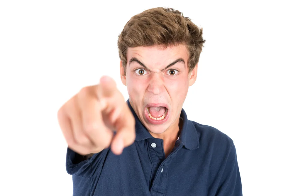 Angry teenage boy making faces isolated in white