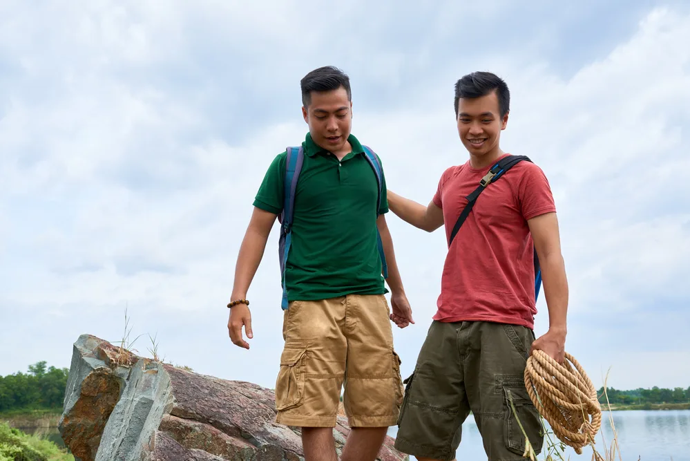 Outdoor climbing instructor patting his friend on back after difficult exercise