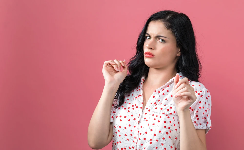 Disgusted face expression with young woman on a solid background