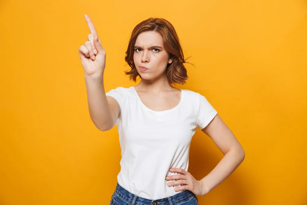 Portrait of a dissatisfied girl standing isolated over yellow background, gesturing