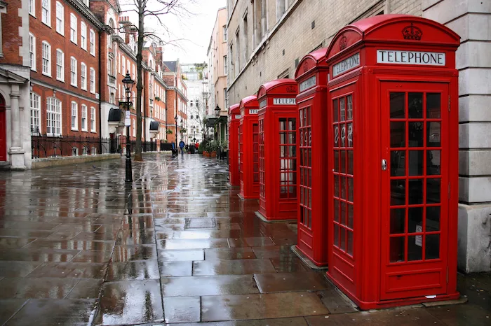 Row of phone booths in rainy London. Street view.