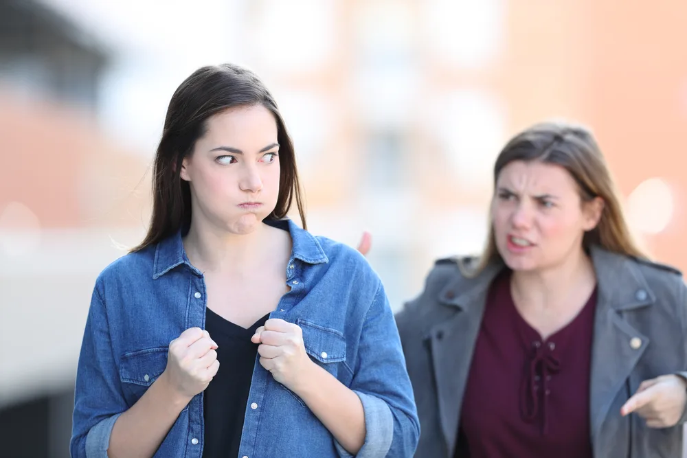 Front view portrait of two angry friends arguing in the street