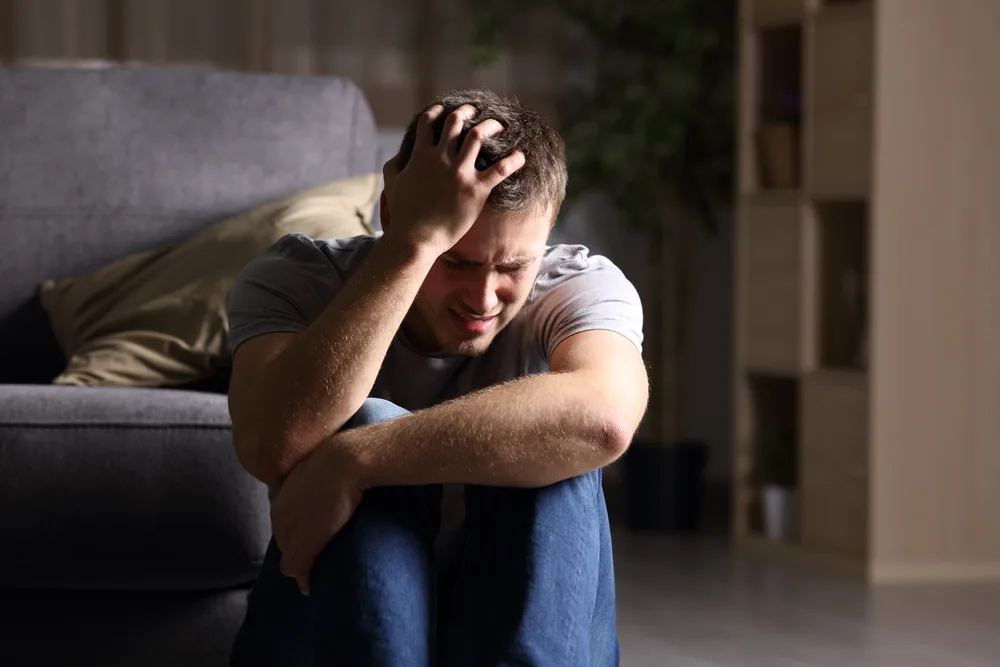 Sad,Man,Lamenting,Sitting,On,The,Floor,In,The,Living