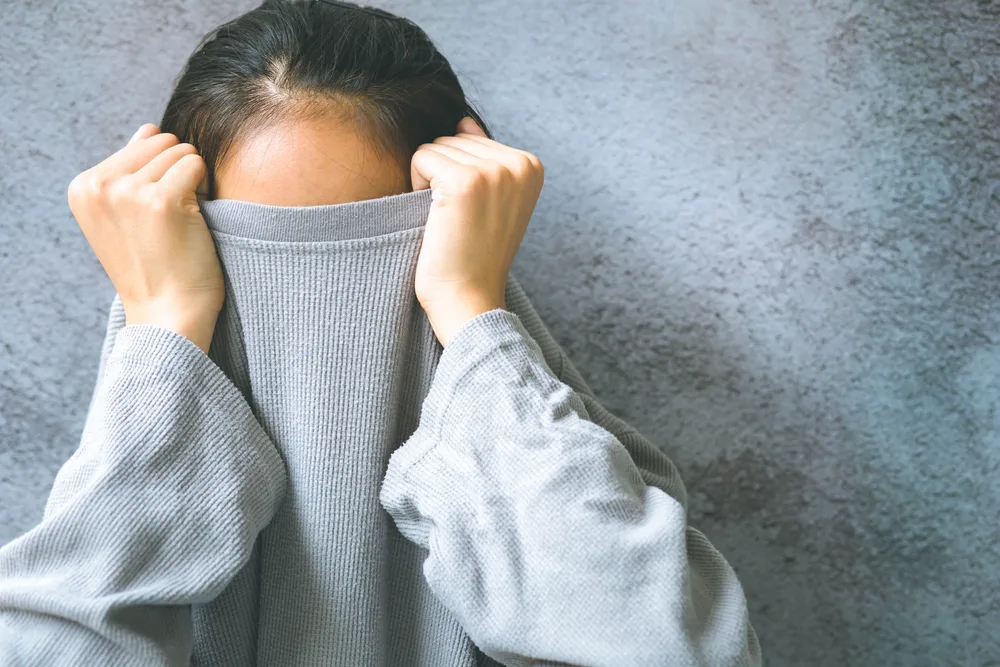 Asian,Woman,Hiding,Face,Under,The,Clothes.,She,Is,Pulling