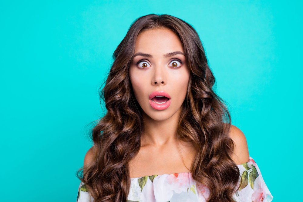 Close up portrait of good-looking, magnificent, exquisite brunette curly woman with big eyes and wide open mouth isolated on vivid teal background