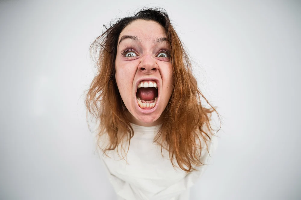 Close-up portrait of insane woman in straitjacket on white background