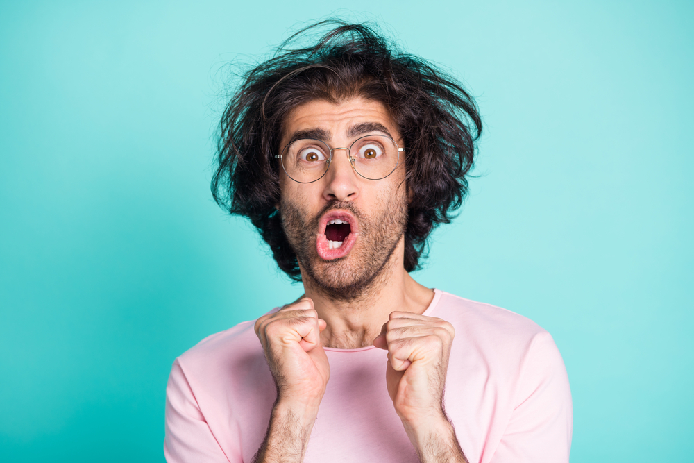 Close up portrait of shocked weird hairdo person fists up yell open mouth isolated on turquoise color background.